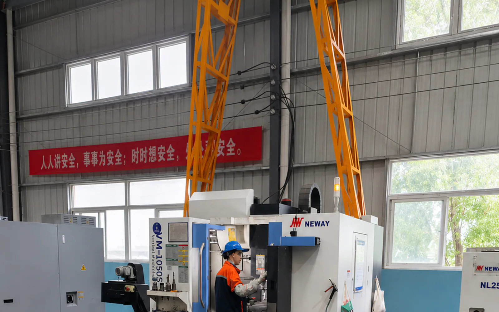 A Chinese operator working at a CNC machining center in a manufacturing workshop